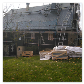 Das Bild zeigt eine Schornsteinbekleidung mit Schiefer  während der Bearbeitung. Zu sehen sind die Mitarbeiter bei der Arbeit.  